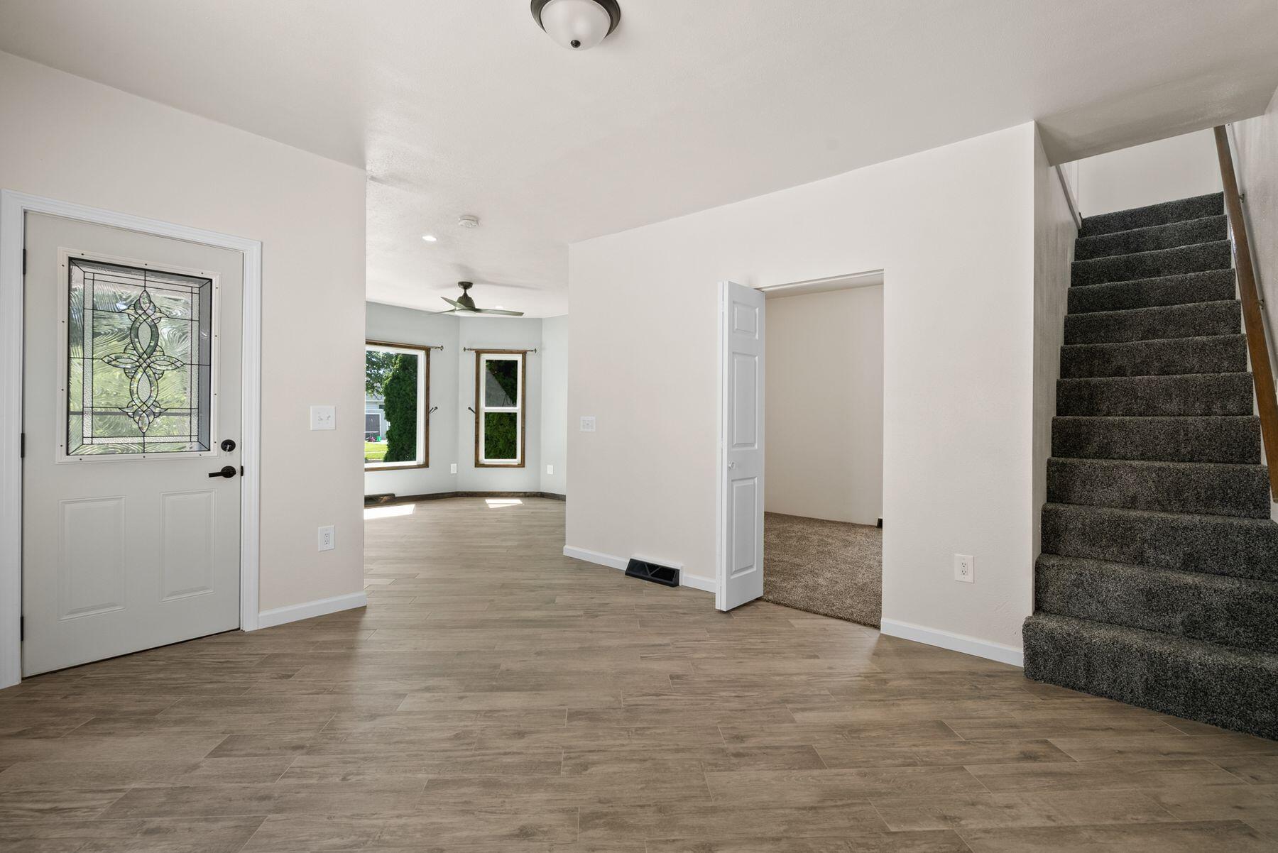 Unfurnished entryway with a decorative glass front door, tiled floor, and carpeted staircase.