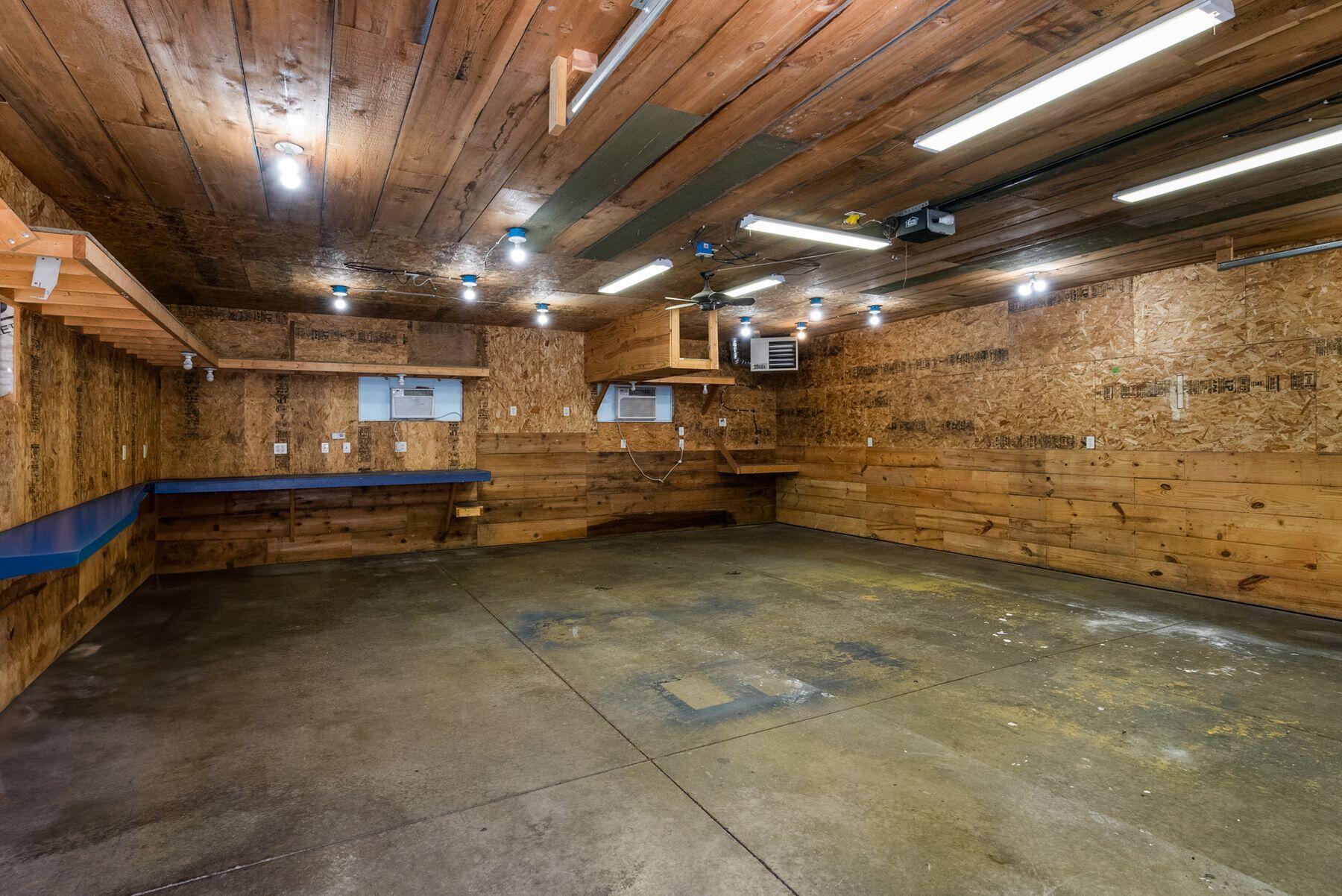 Wood-paneled garage with a concrete floor, overhead lights, and a built-in workbench.