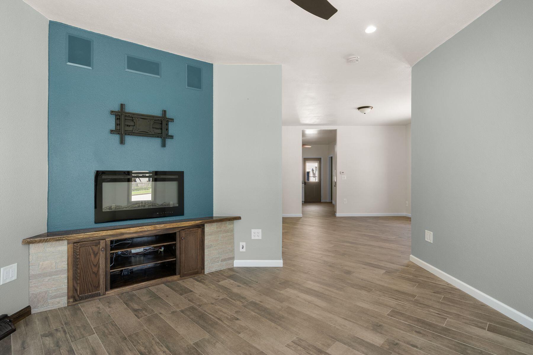 Living room with an electric fireplace on a blue accent wall and wood-look tile floors.