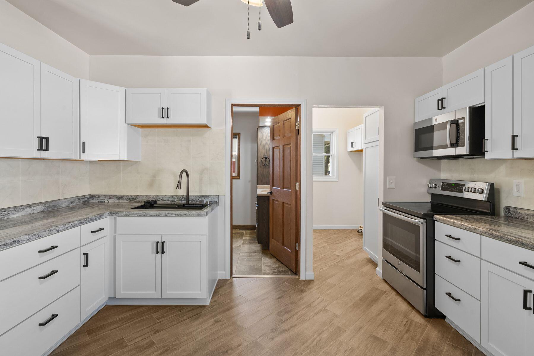 Renovated kitchen with white cabinets, gray countertops, and stainless steel appliances.