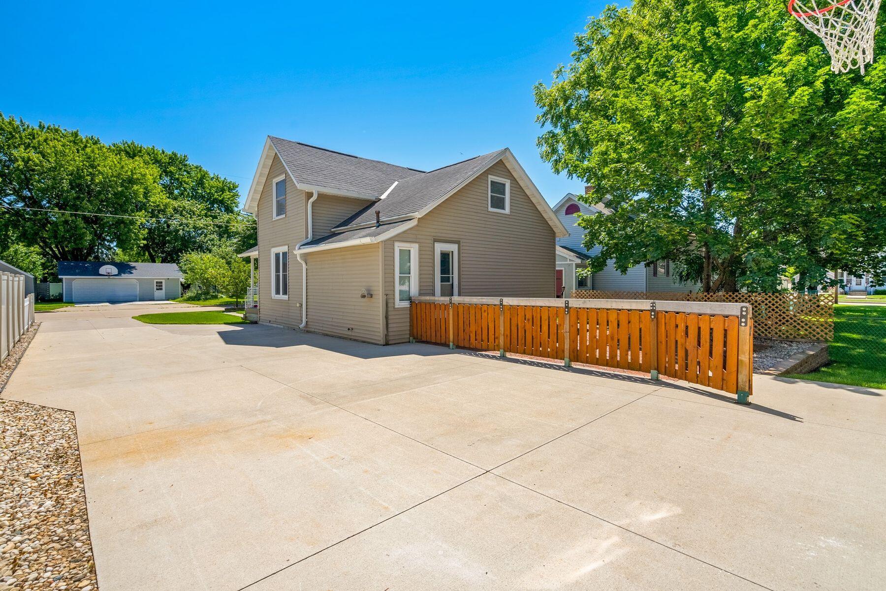 House exterior with a wide concrete driveway and orange wooden fence