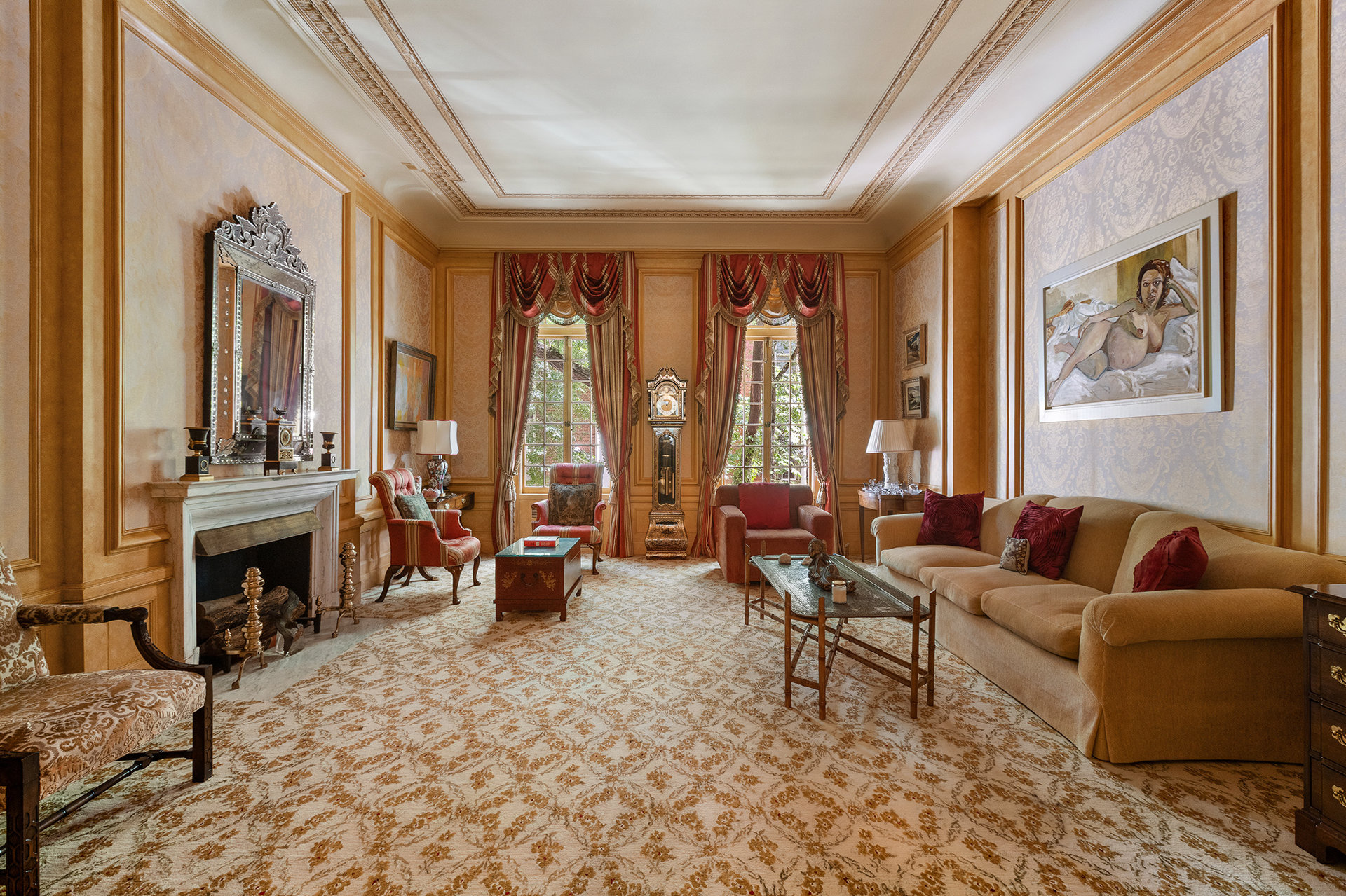 Formal living room with a marble fireplace, ornate paneling, tall curtained windows, and beige sofa.