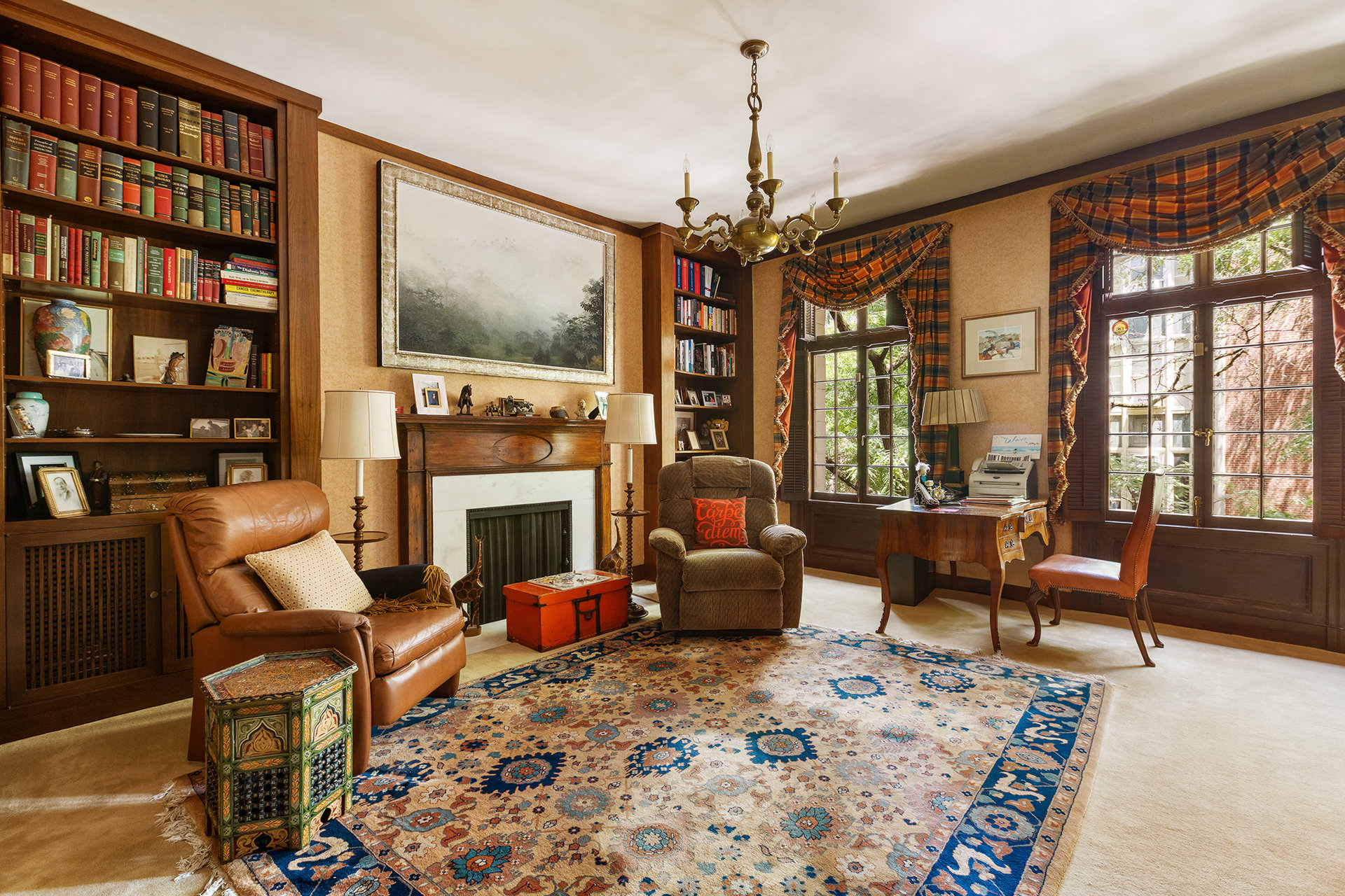 Furnished living room with built-in bookshelves, a fireplace, and tall windows.