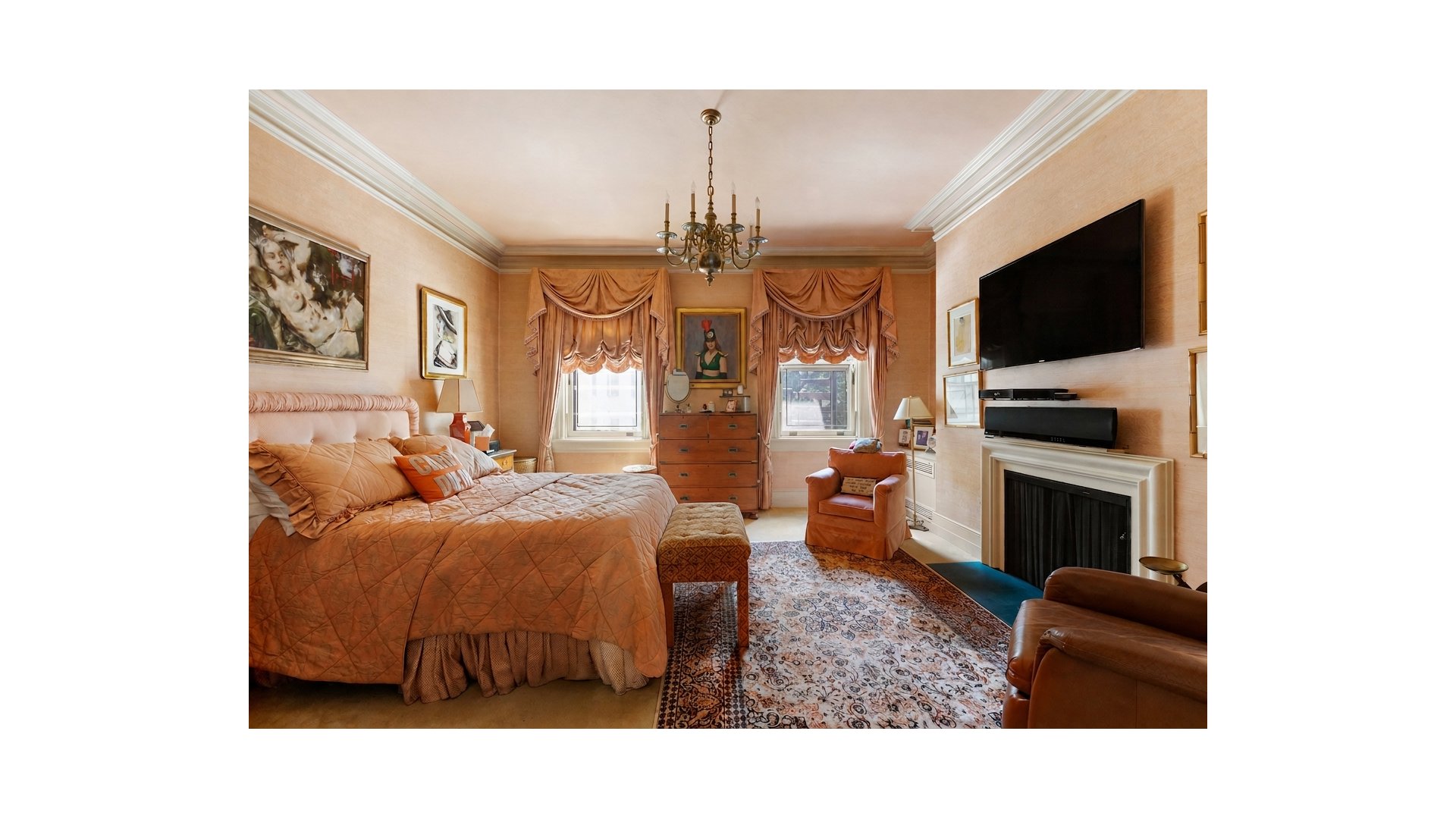 Bedroom with an upholstered bed, ornate draped curtains, and a fireplace beneath a large television.