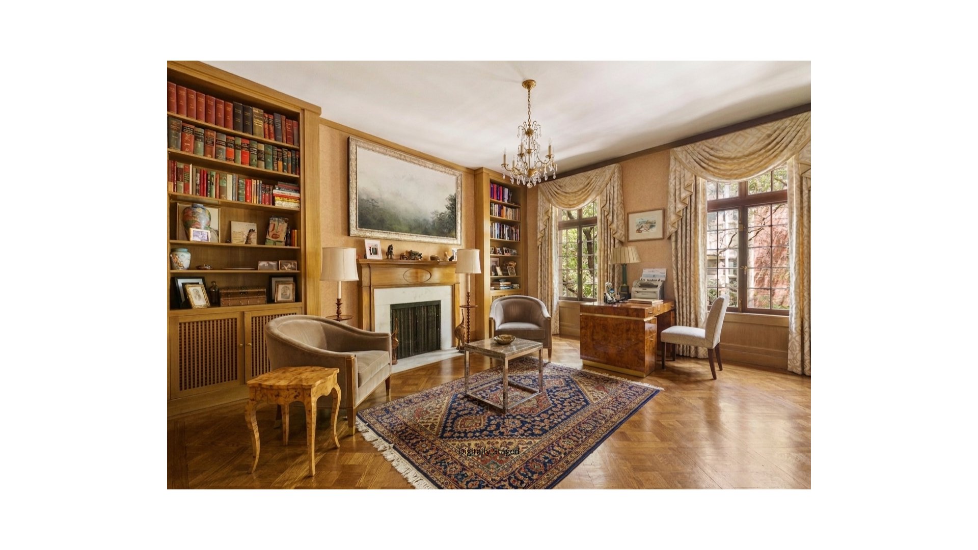 Staged library with built-in bookcases, a fireplace, and a writing desk beside tall windows.