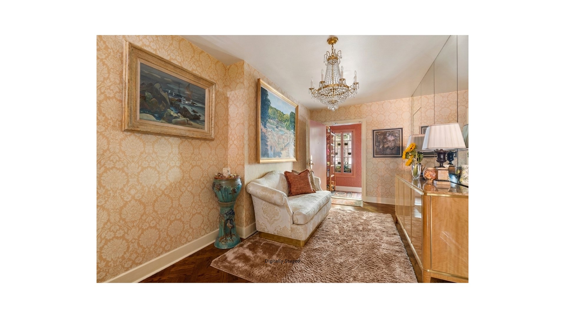 Sitting room with patterned gold wallpaper, cream sofa, crystal chandelier, and mirrored panels.