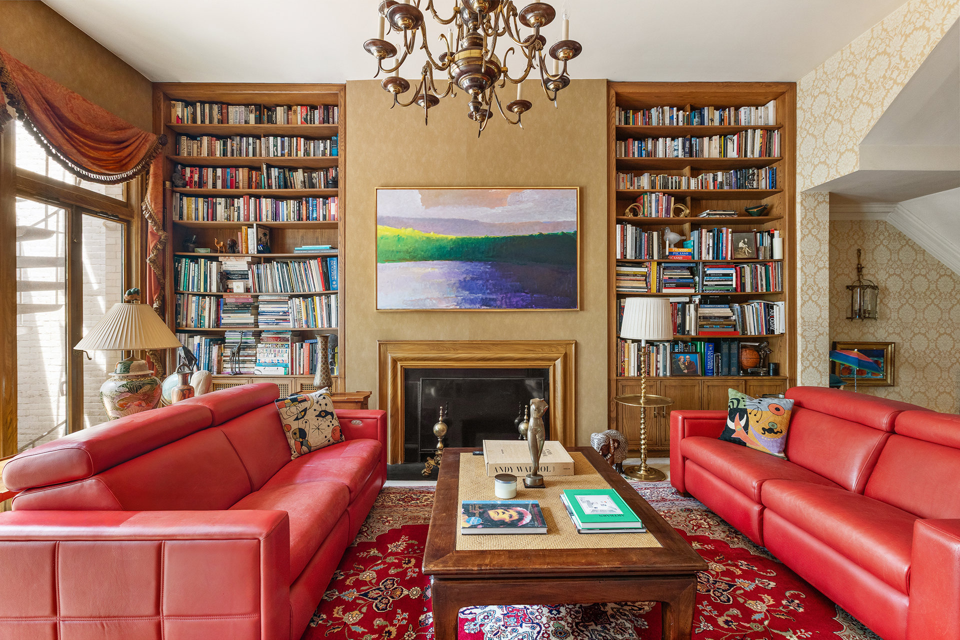 Living room with red leather sofas, a fireplace, and book-filled built-in shelves.