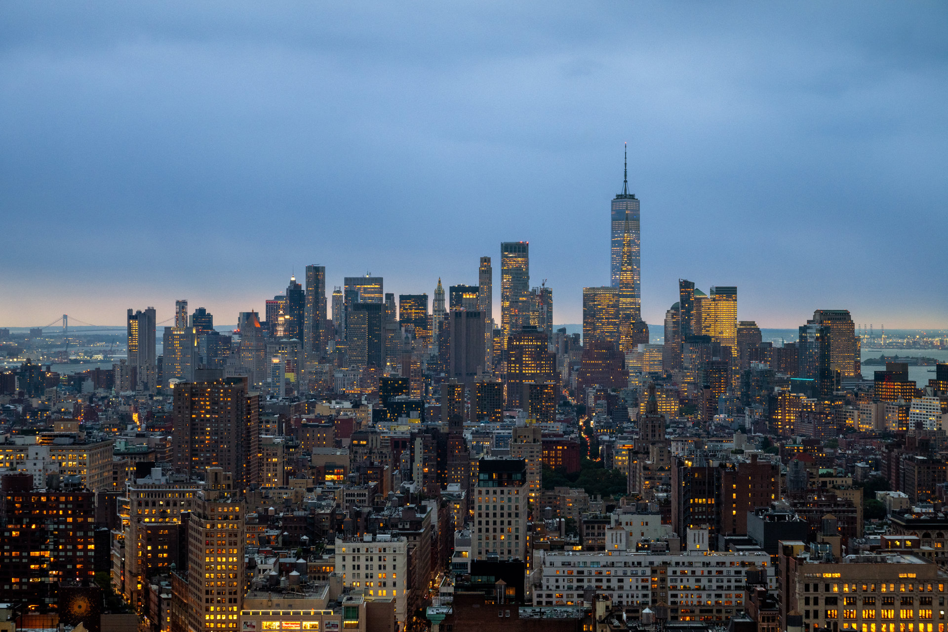 Manhattan skyline at dusk, with One World Trade Center above the illuminated city.