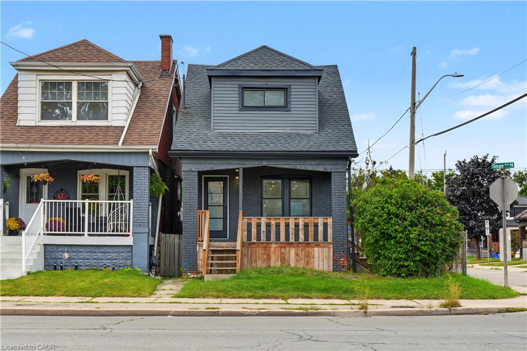 Gray-brick house with a steep roof and a small wooden-railed front porch.