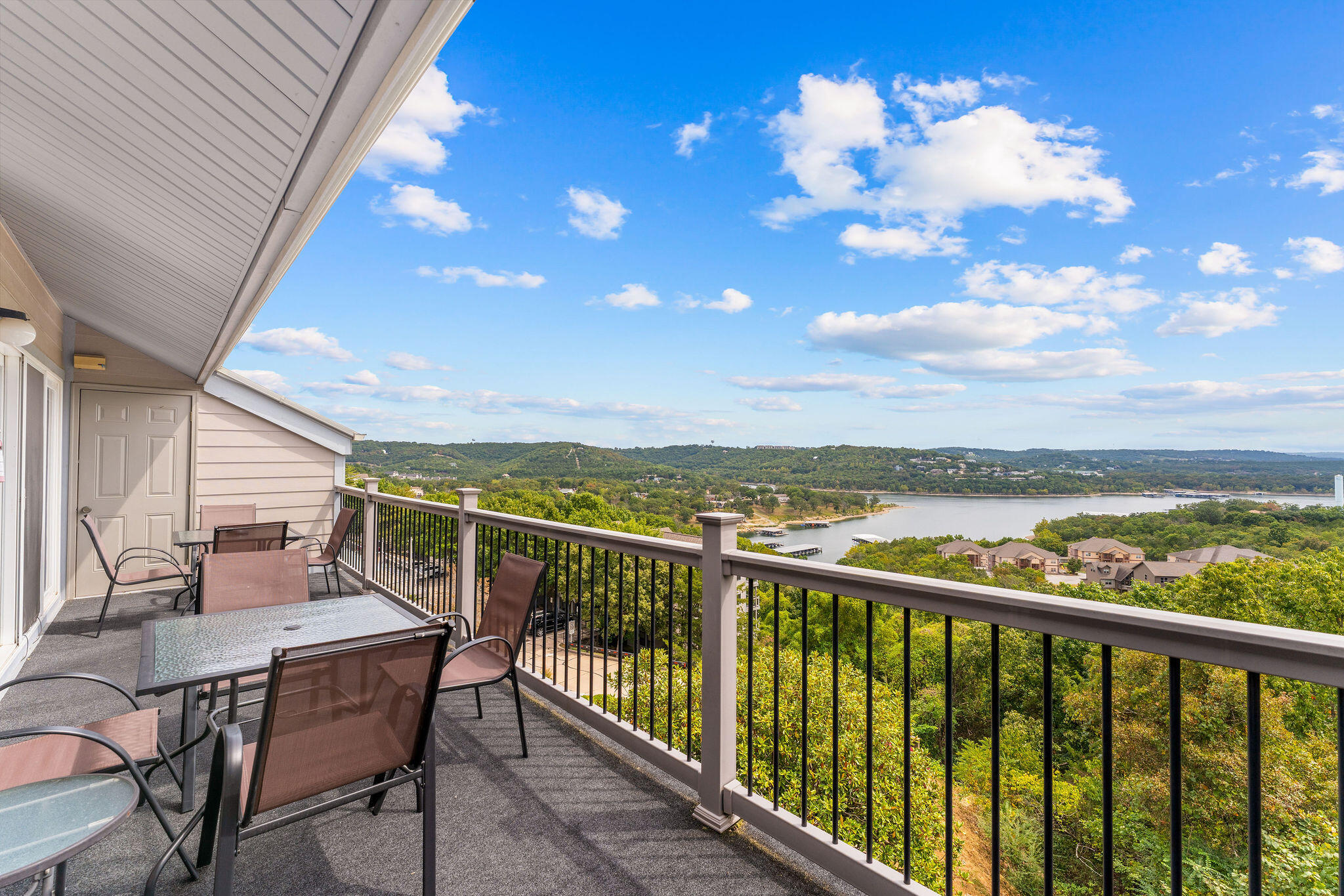 Furnished balcony overlooking a lake and wooded hills.