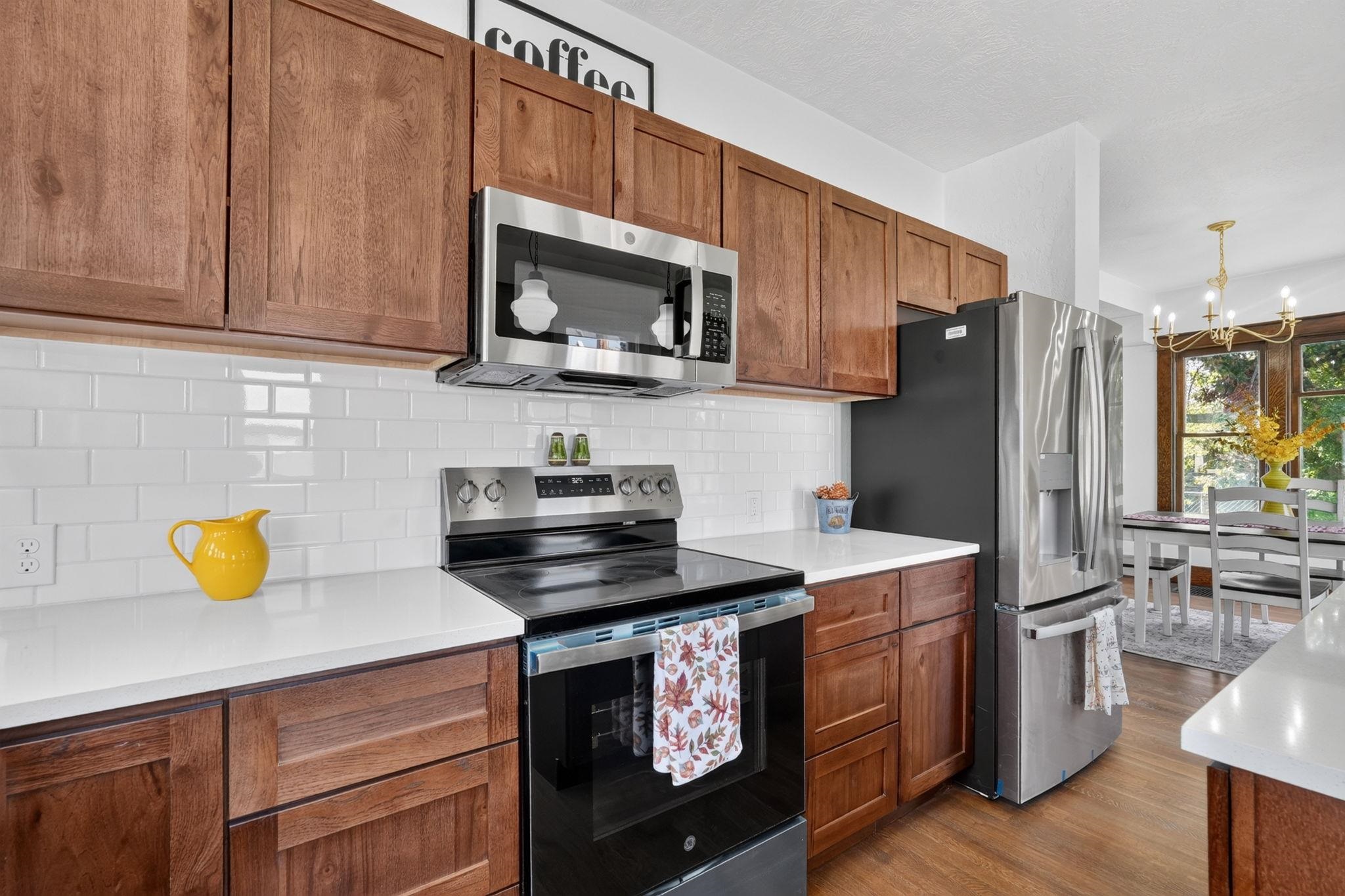 Kitchen with wood cabinets, white tile backsplash, stainless steel appliances, and an adjoining dining area.