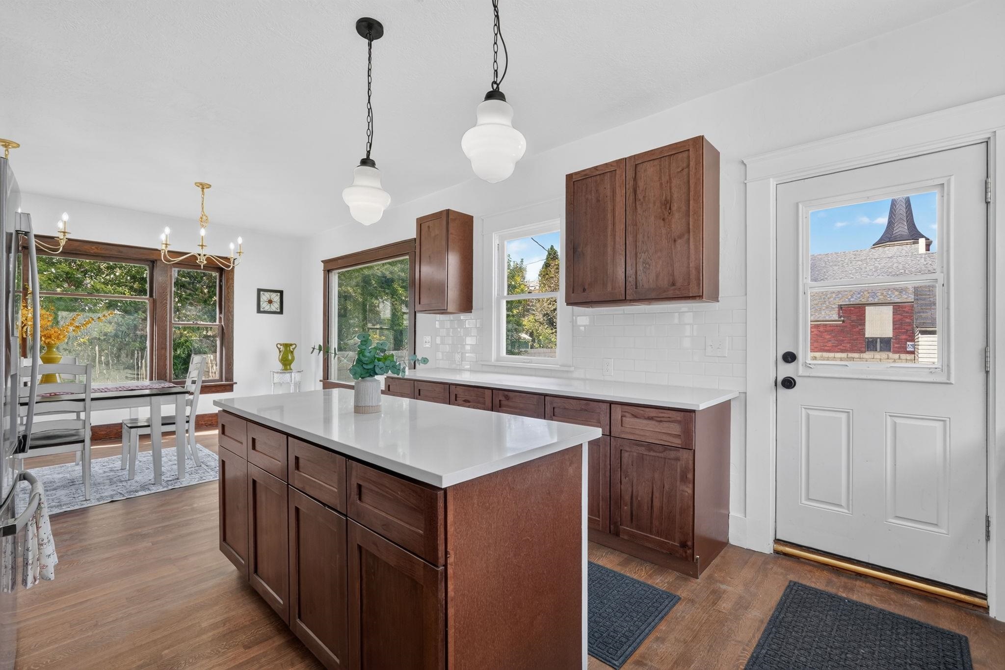 Kitchen with dark wood cabinetry, a large white-topped island, and an adjoining dining area.