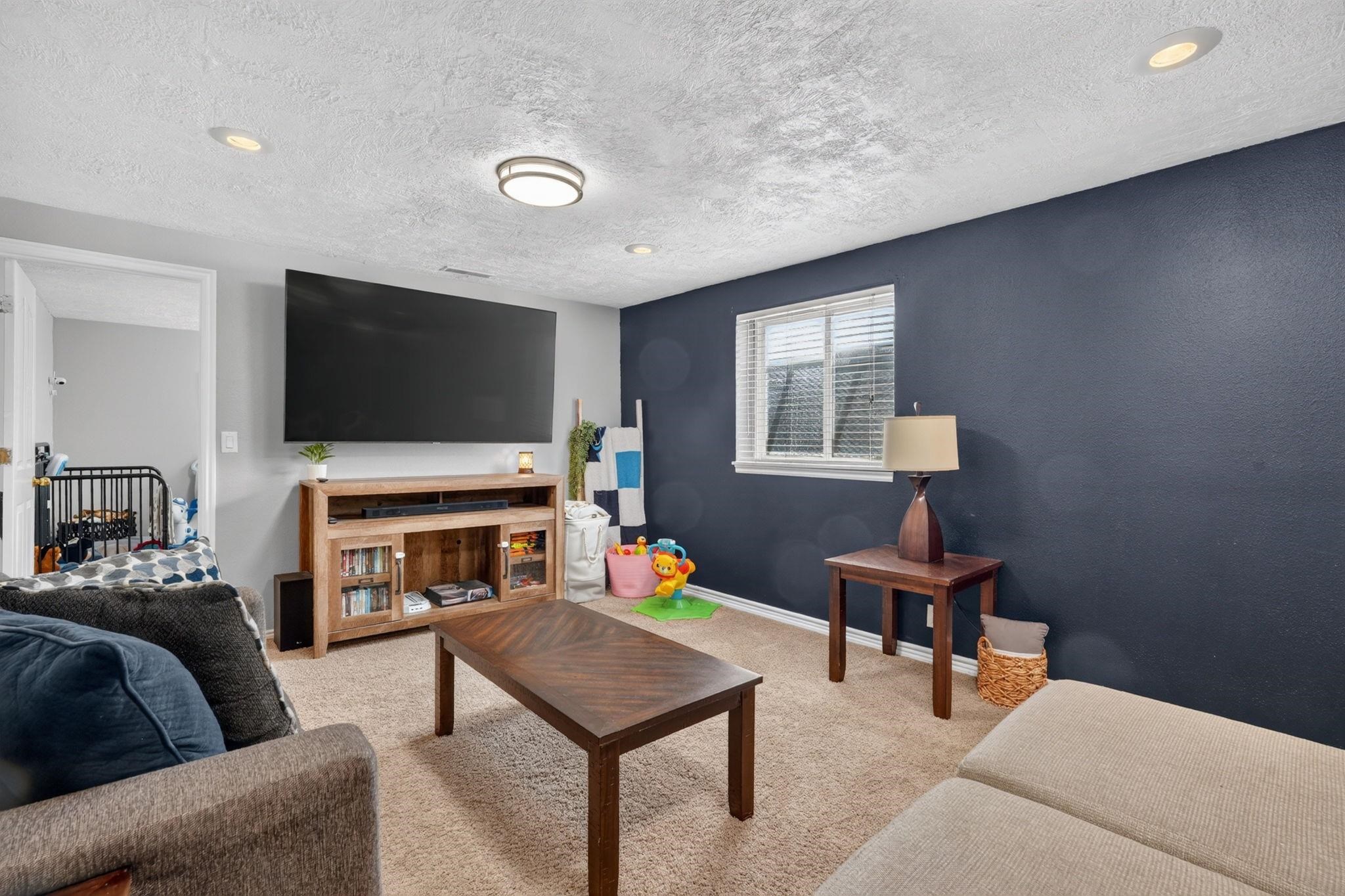Living room with a dark blue accent wall, wall-mounted television, and wooden coffee table.