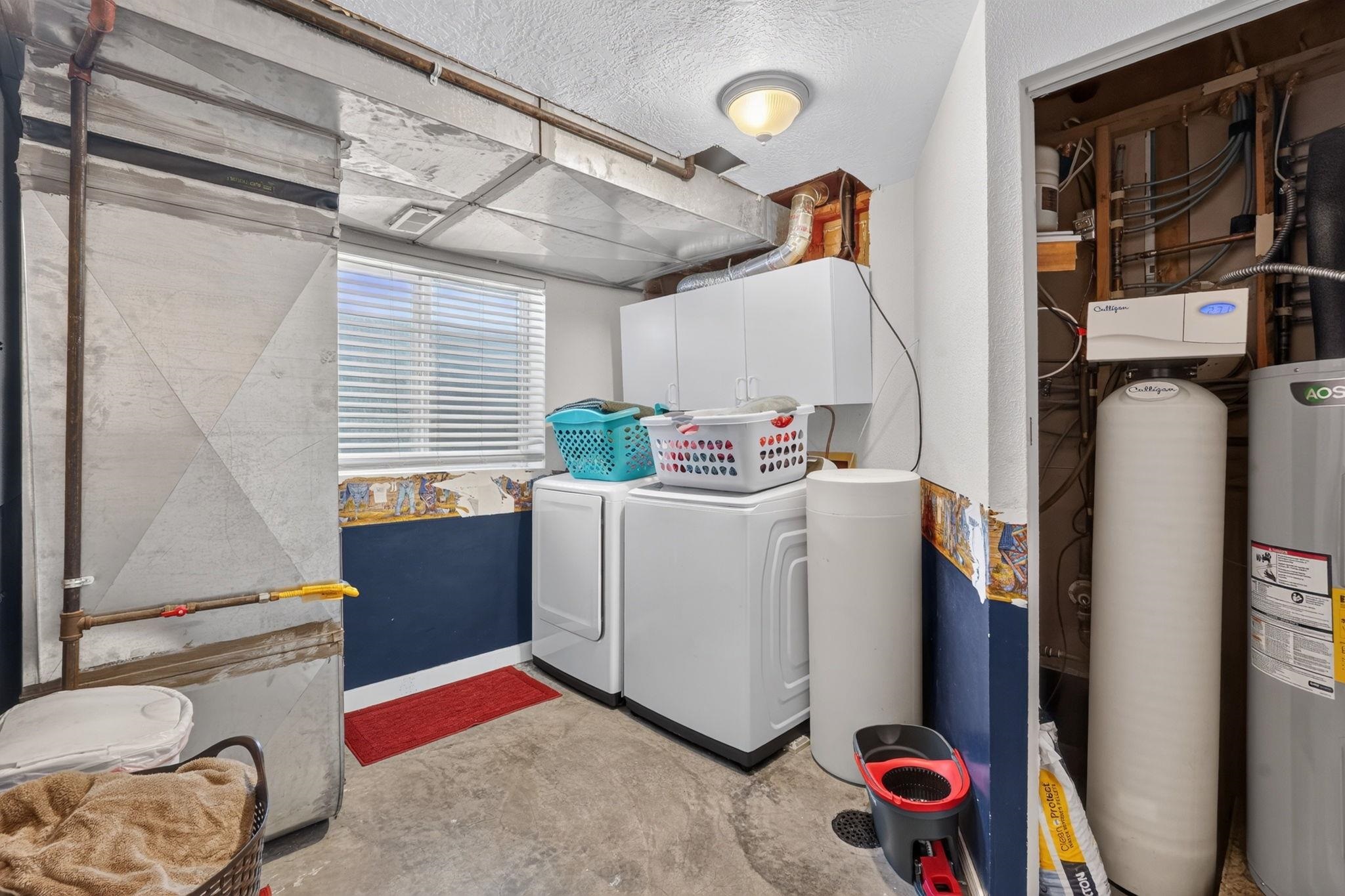 Laundry room with a washer and dryer, white cabinets, and exposed utility equipment.
