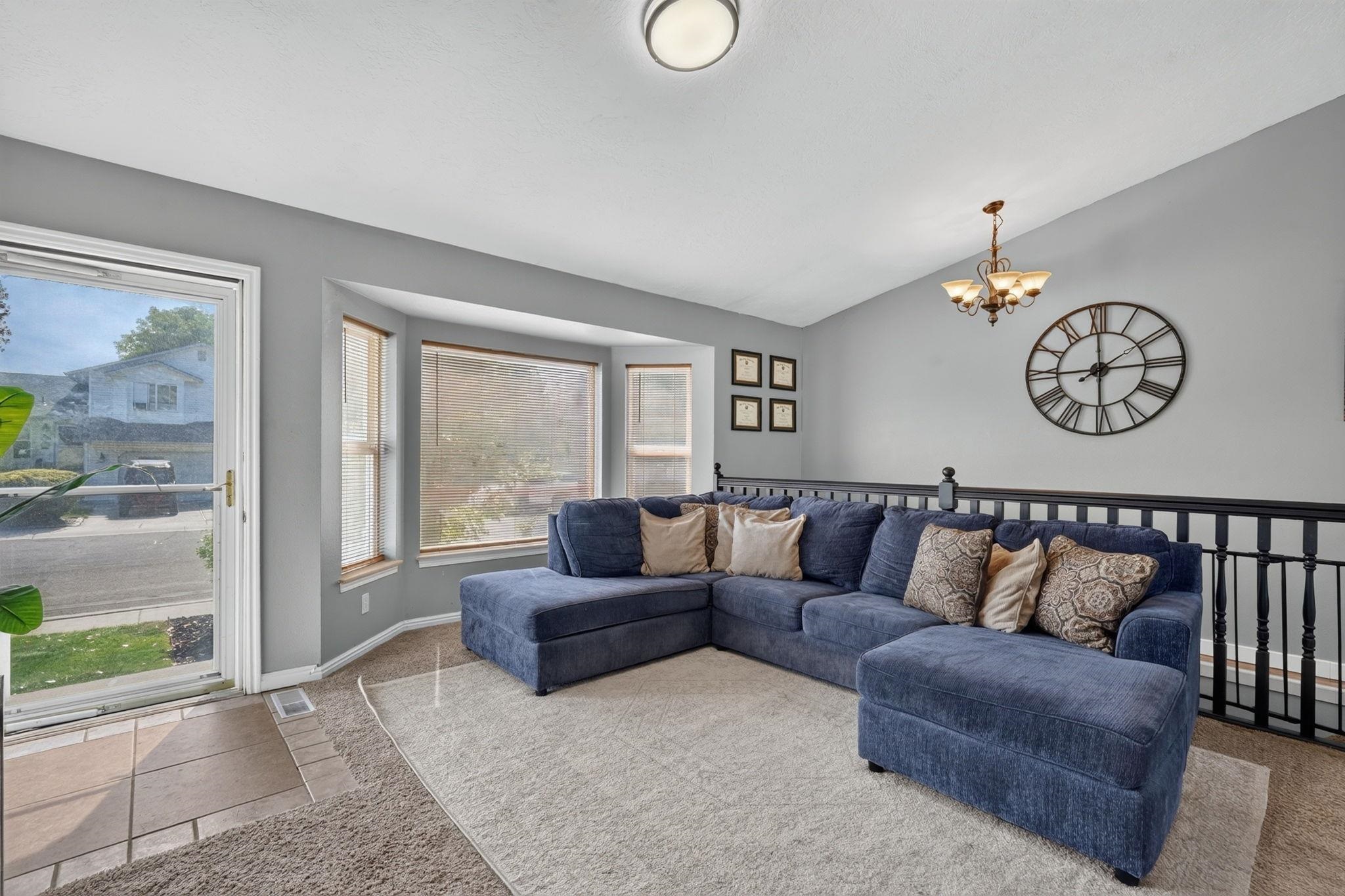 Living room with a blue sectional, bay windows, and a large wall clock.
