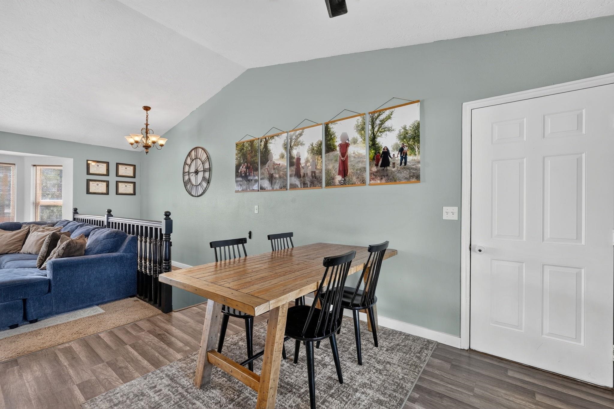 Dining area with a rustic wooden table and black chairs beside a blue sofa.