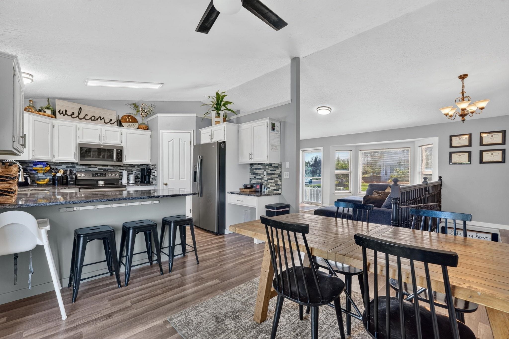 Open-plan kitchen and dining area with white cabinets, a wooden table, and a living room beyond.
