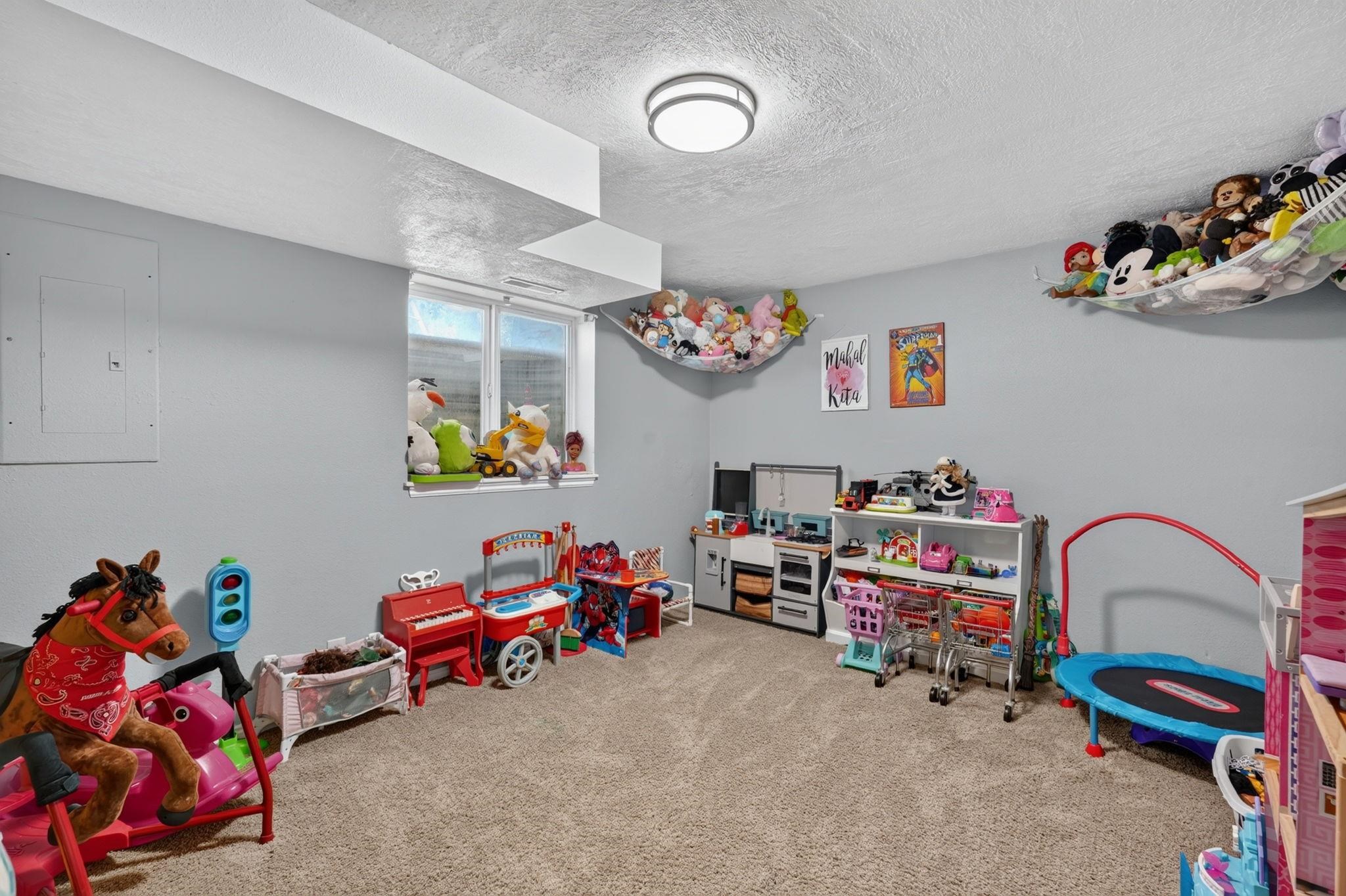 Playroom with toy kitchens, stuffed animals in hammocks, a ride-on horse, and a small trampoline.