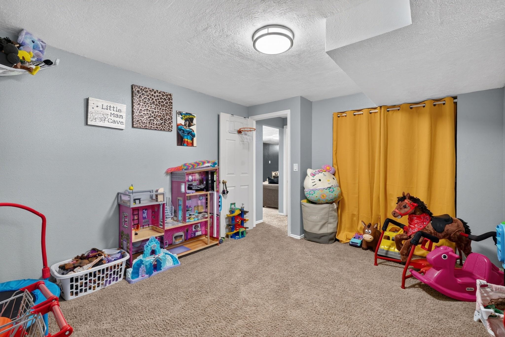 Children’s playroom with dollhouses, toy vehicles, stuffed animals, and bright yellow curtains.