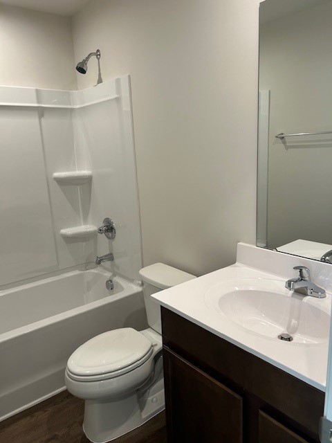 Bathroom with a tub and shower, toilet, and dark wood vanity with a white sink.