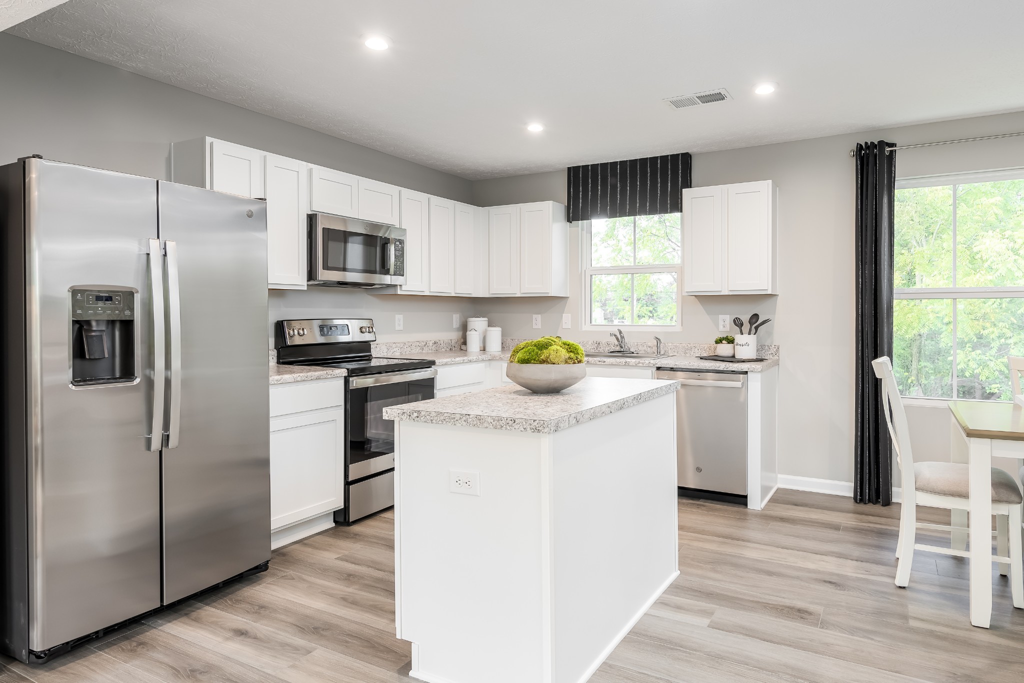 Kitchen with white cabinets, stainless steel appliances, and a large granite-topped island.