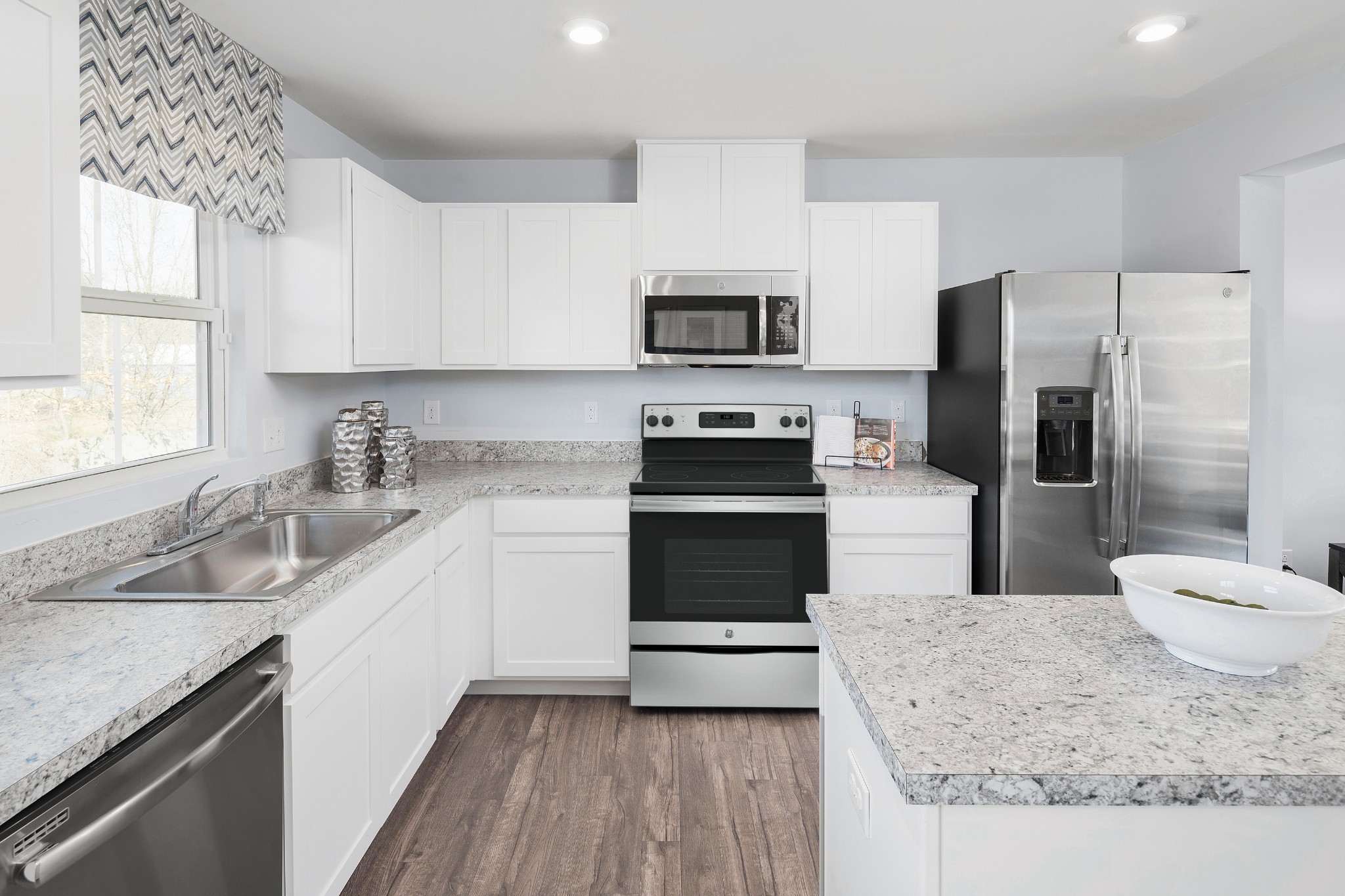 Kitchen with white cabinets, stainless steel appliances, stone counters, and a large island.