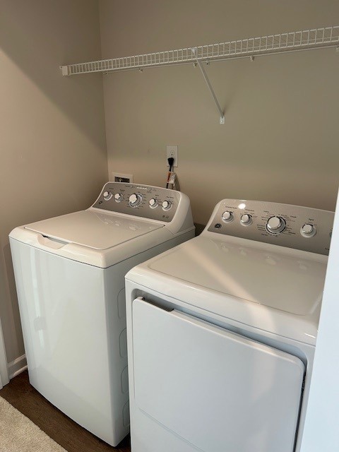 Laundry room with a white washer and dryer beneath a wire shelf.