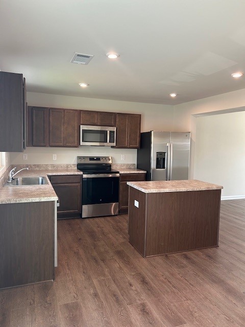 Kitchen with dark cabinets, a central island, and stainless steel appliances.