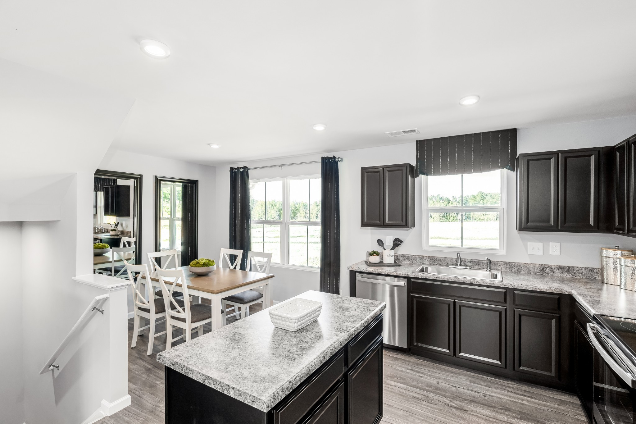 Kitchen with dark cabinets, granite island, stainless appliances, and an adjoining dining area.