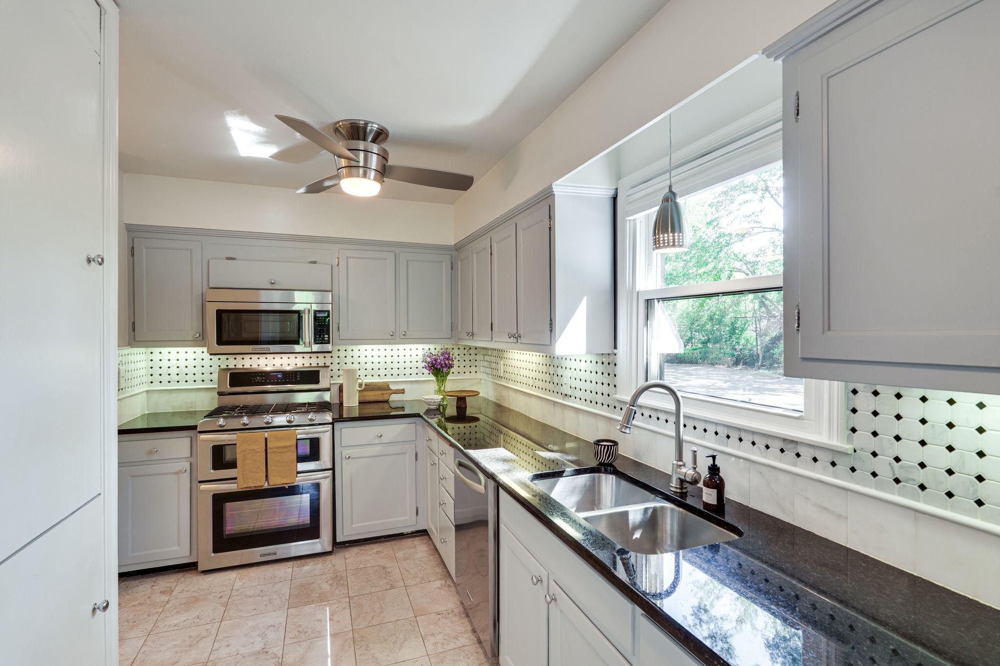 Kitchen with gray cabinets, black countertops, a double sink, and stainless steel appliances.