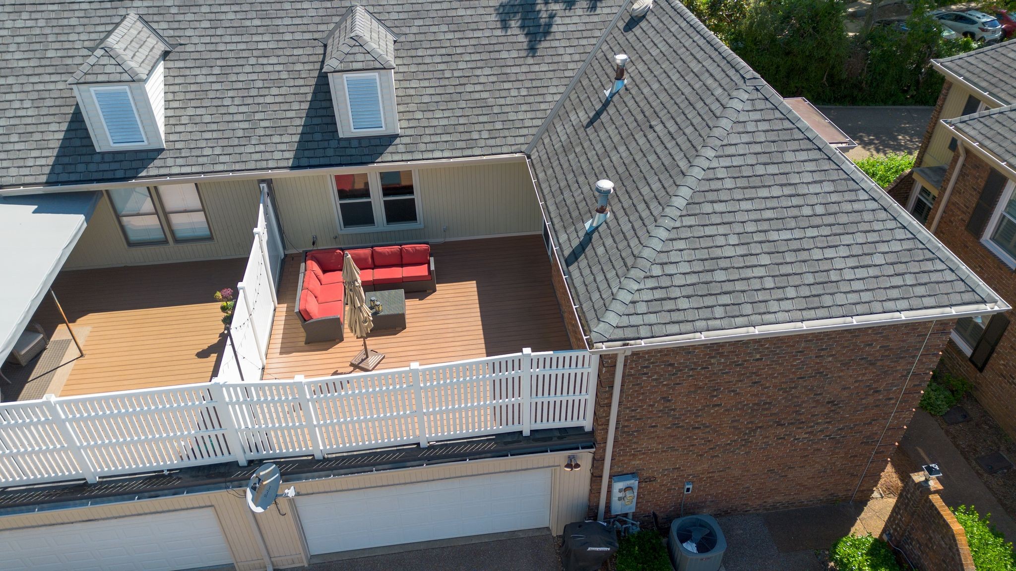 Aerial view of a rooftop deck with a red sectional sofa and white railing.