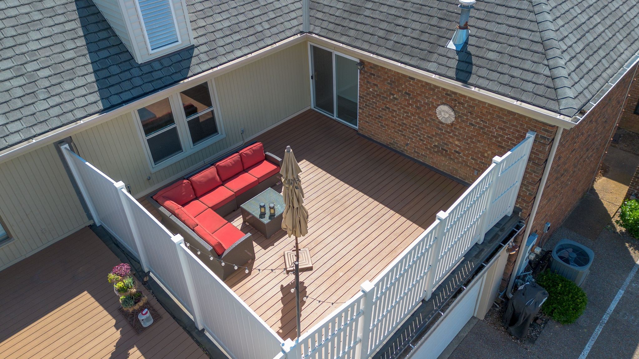 Raised wooden deck with white railings and a red-cushioned sectional sofa.