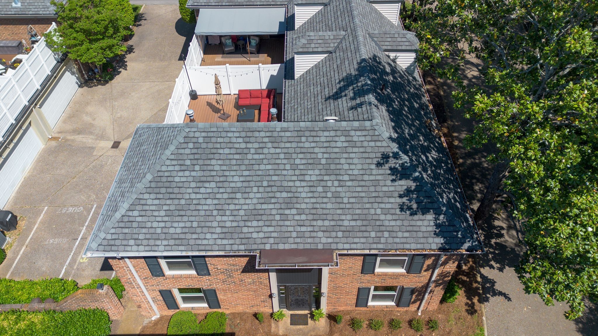 Aerial view of a brick house with a gray roof and furnished rooftop patio.