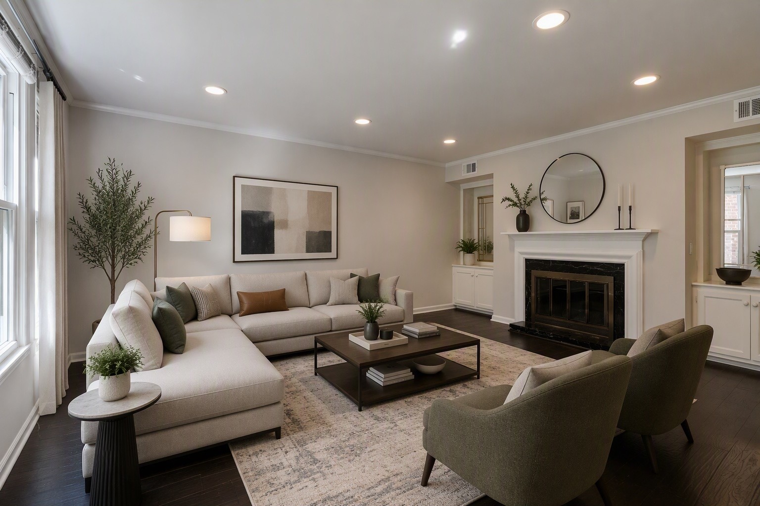 Staged living room with a cream sectional, olive chairs, patterned rug, and white fireplace.