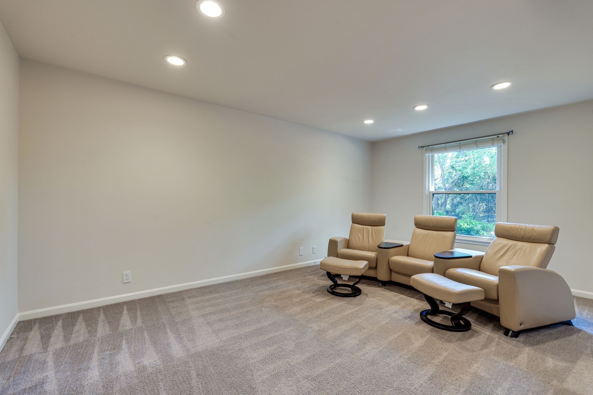Furnished room with three tan leather reclining chairs beside a window.