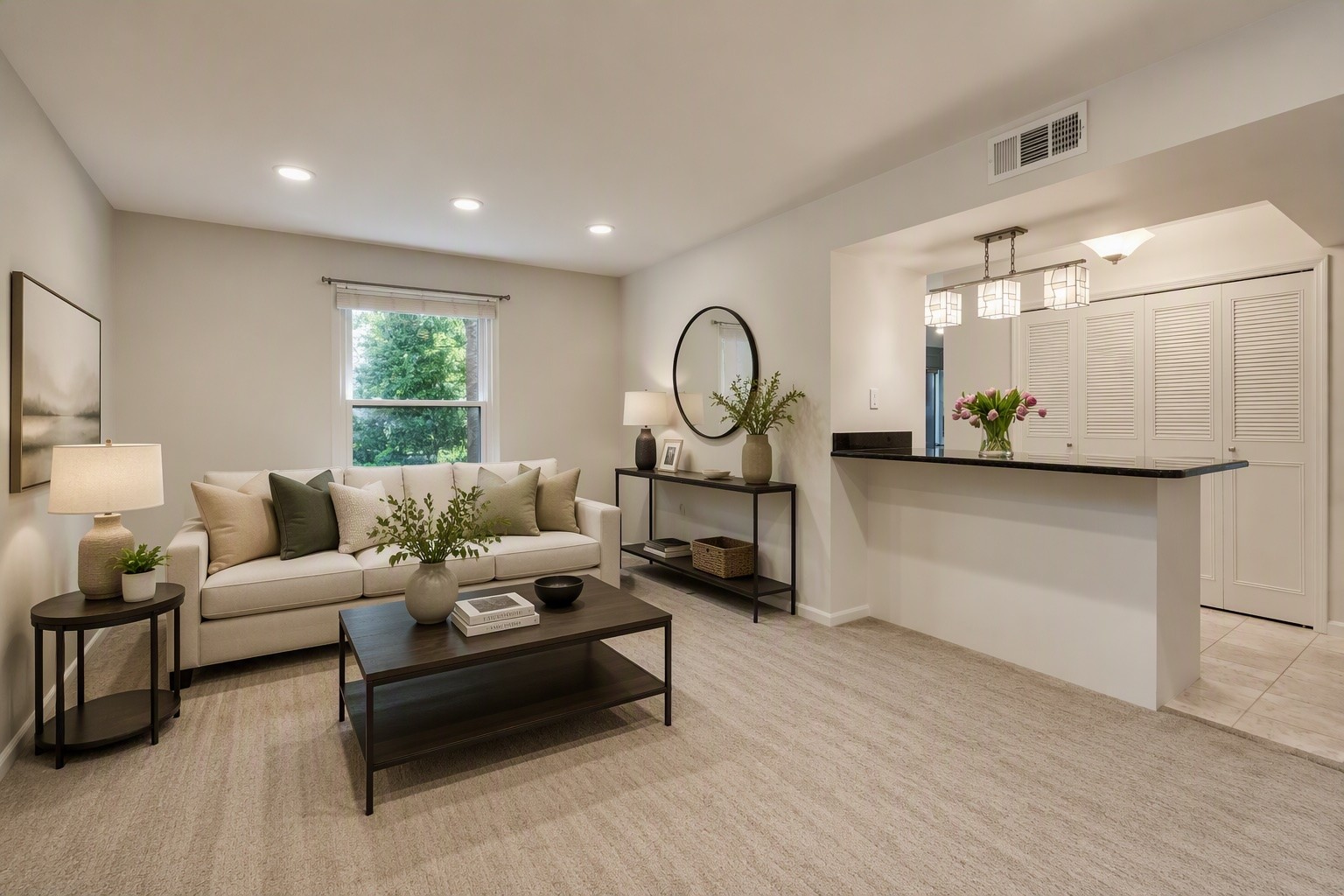 Living room with a cream sofa and dark coffee table beside a kitchen breakfast bar.