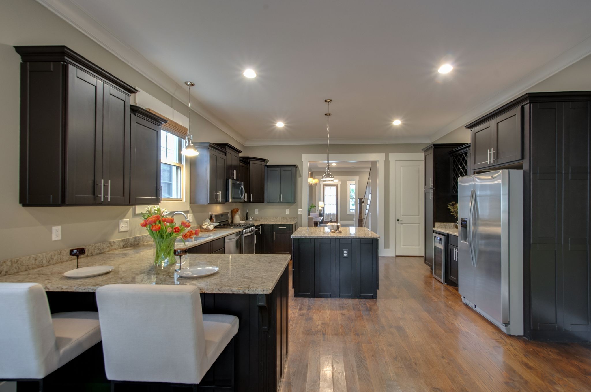 Kitchen with dark cabinetry, granite counters, a central island, and stainless steel appliances.