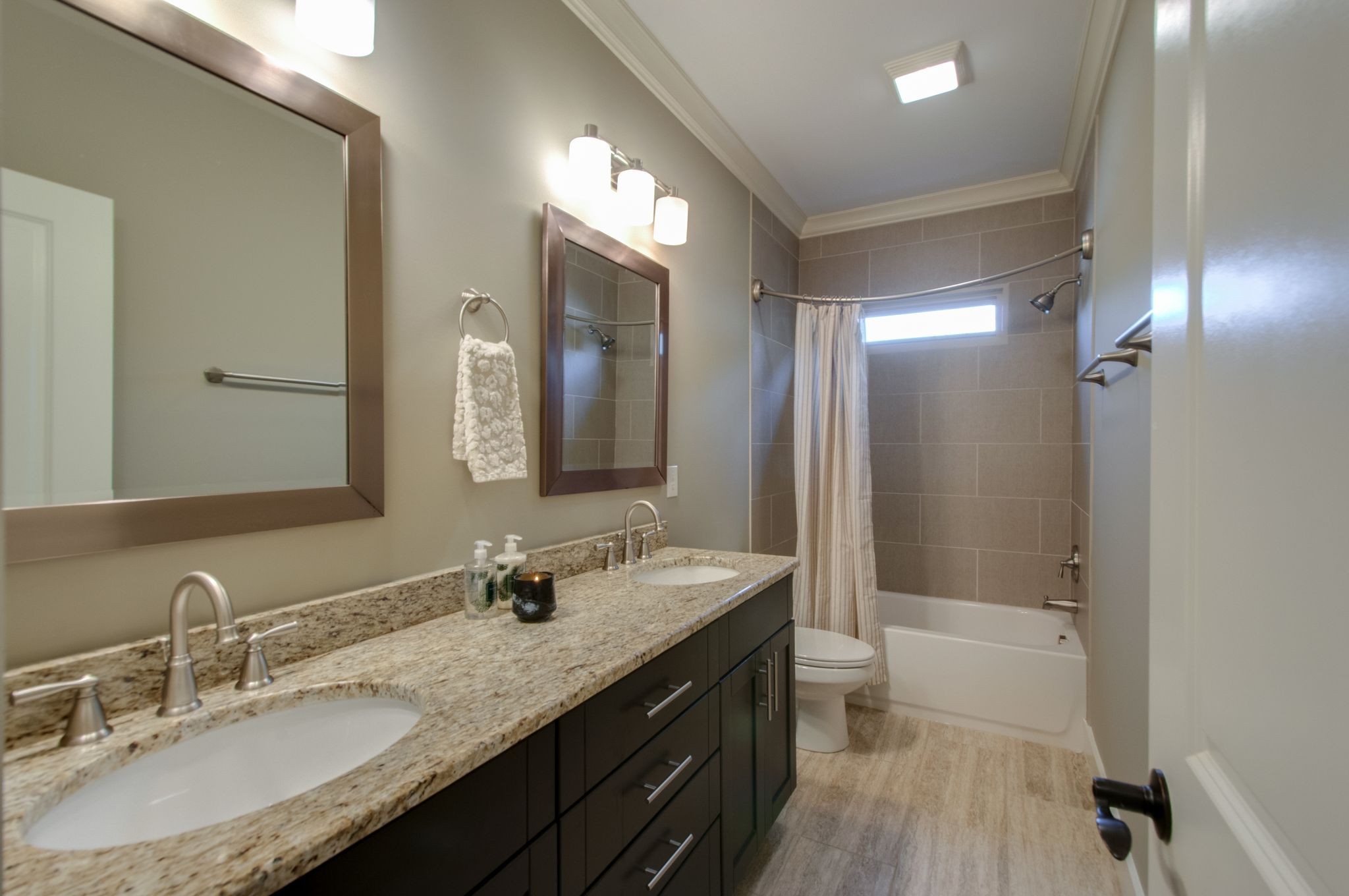 Bathroom with a double-sink granite vanity and tiled tub and shower.