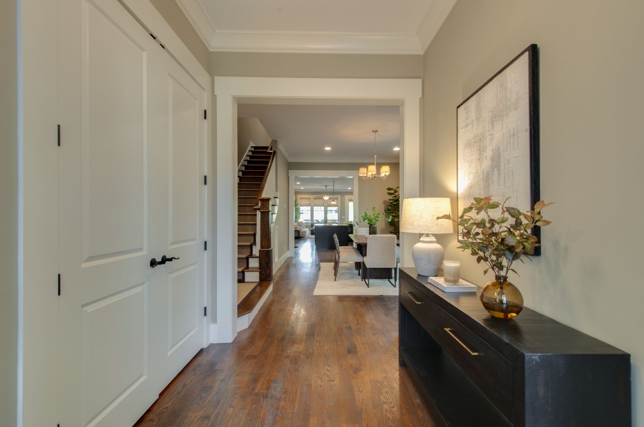 Entry hall with hardwood floors, a dark console table, and a staircase opening onto the dining area.