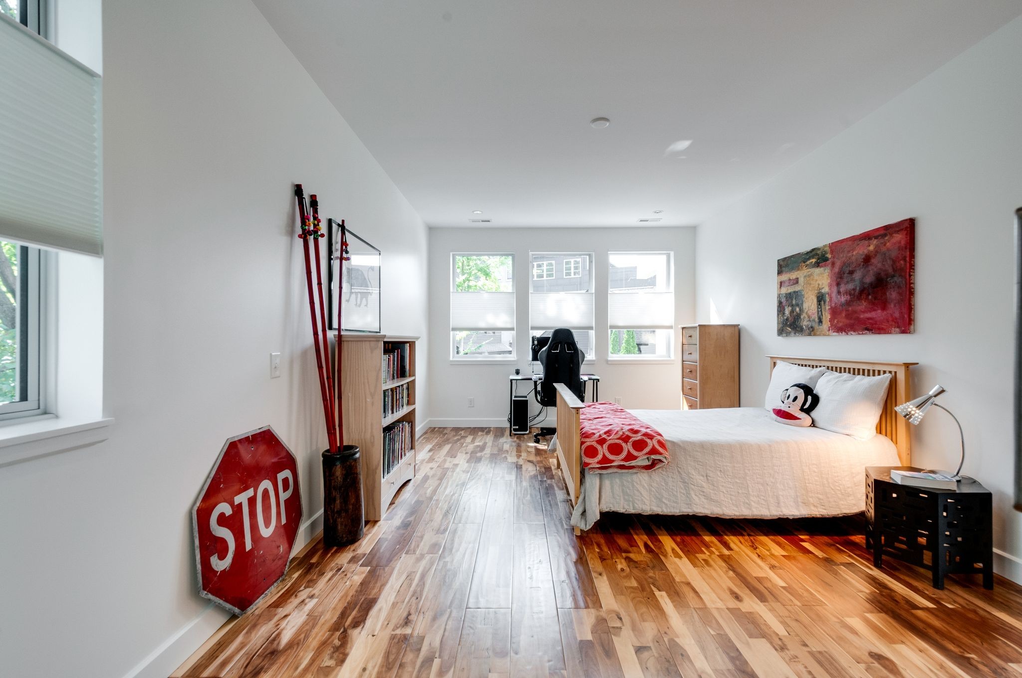 Furnished bedroom with hardwood floors, a wooden bed, and a red STOP sign leaning against the wall.