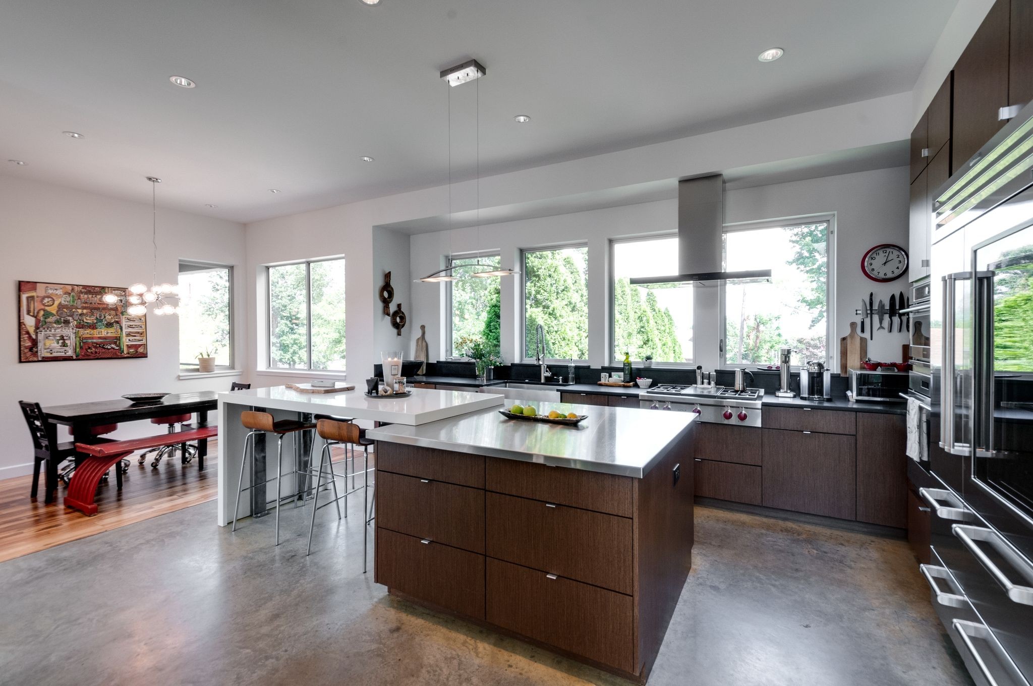 Modern kitchen with a large island, dark wood cabinetry, stainless steel appliances, and adjoining dining area