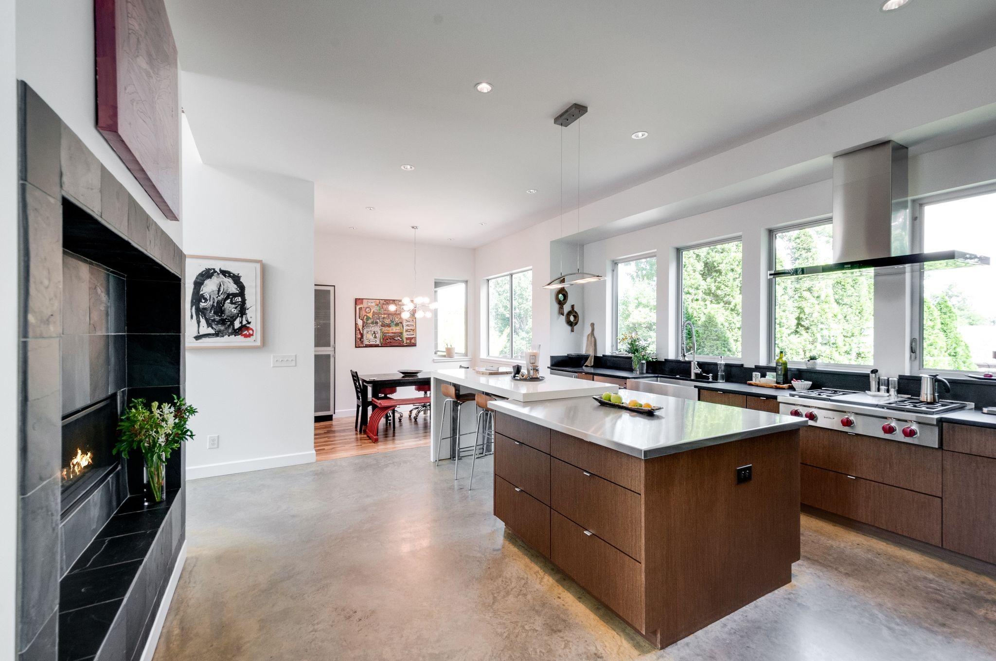 Modern kitchen with a large wood-paneled island, stainless-steel range, and adjoining dining area.