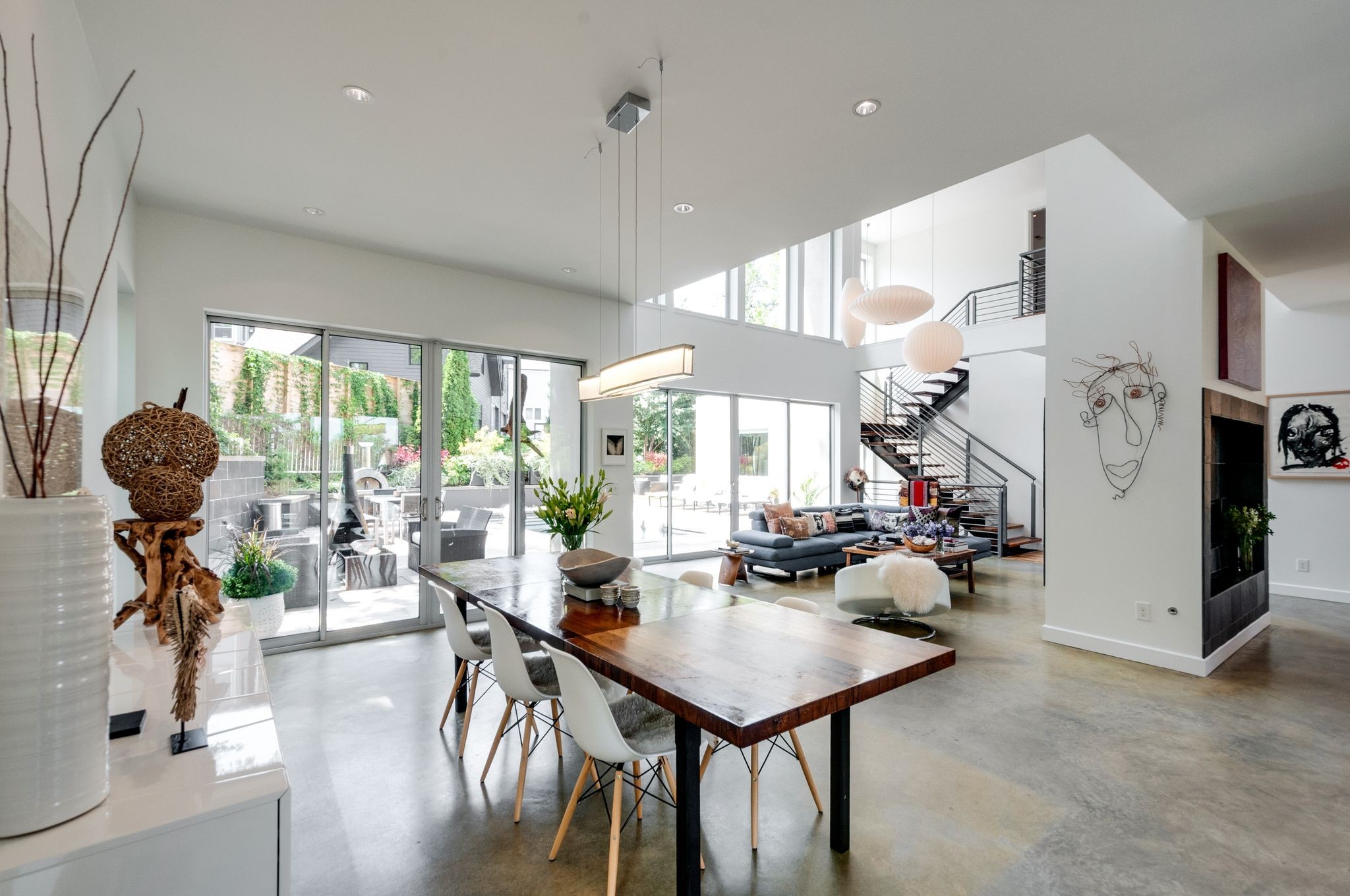 Open-plan living and dining room with a wood table, gray sectional, and glass doors to a patio.