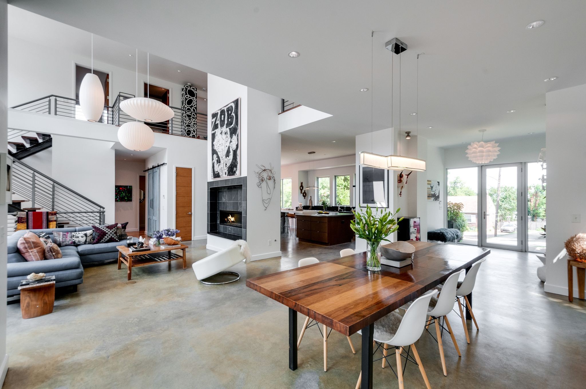 Open-plan living and dining room with a wood table, staircase, fireplace, and kitchen.