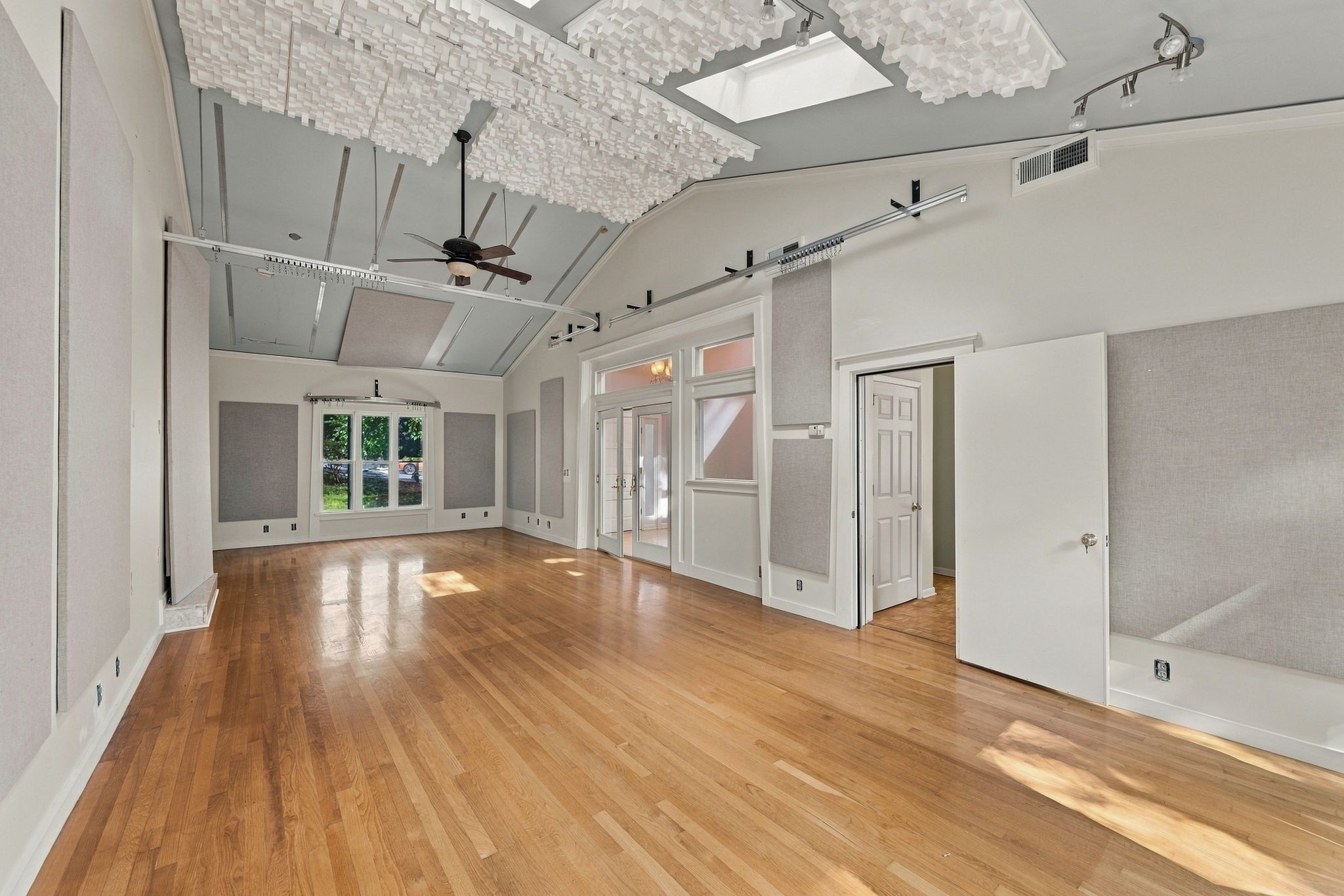 Vacant room with hardwood floors, acoustic wall panels, and suspended ceiling panels