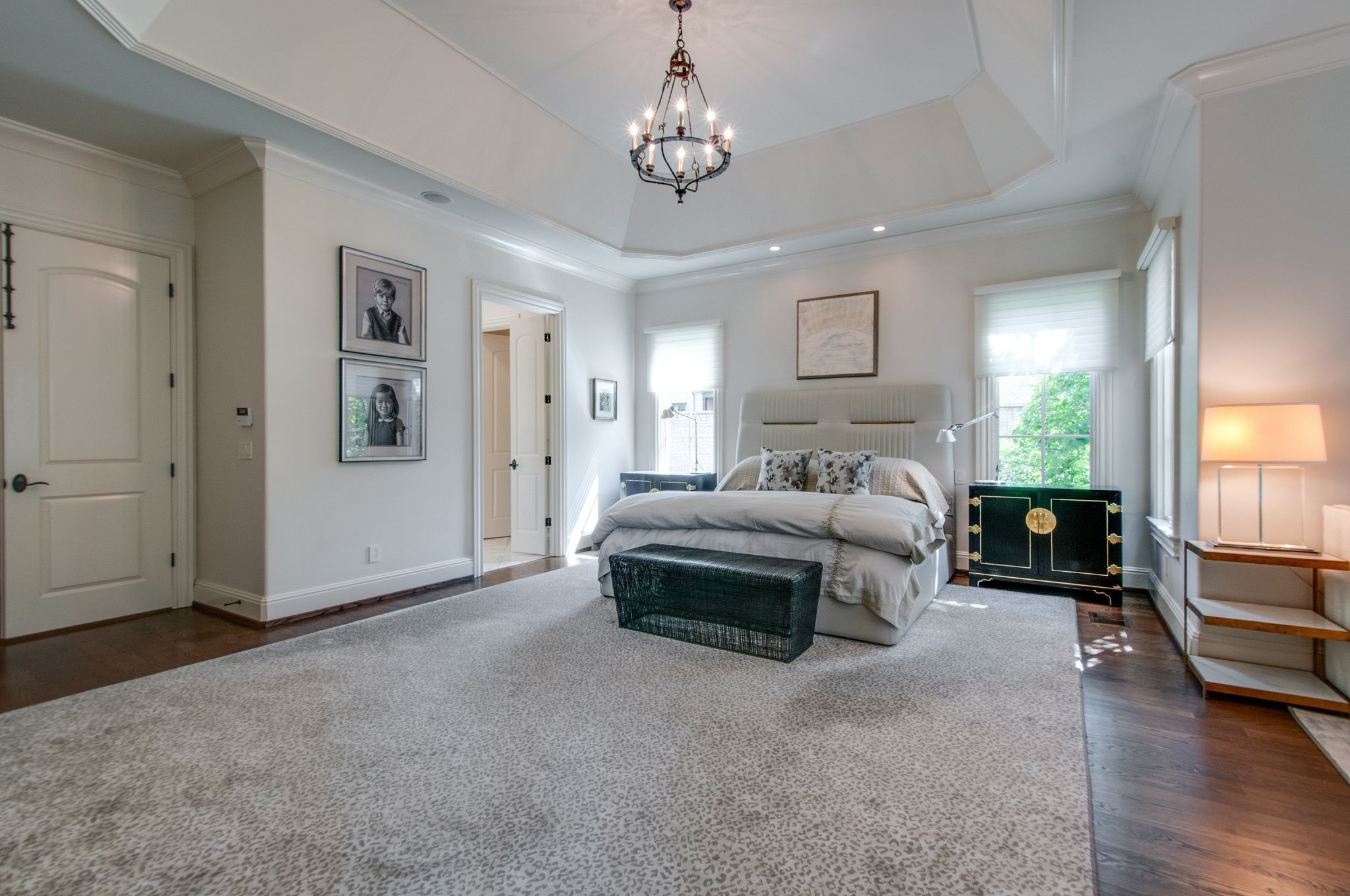 Bedroom with an upholstered bed, patterned rug, and dark green bedside cabinet.