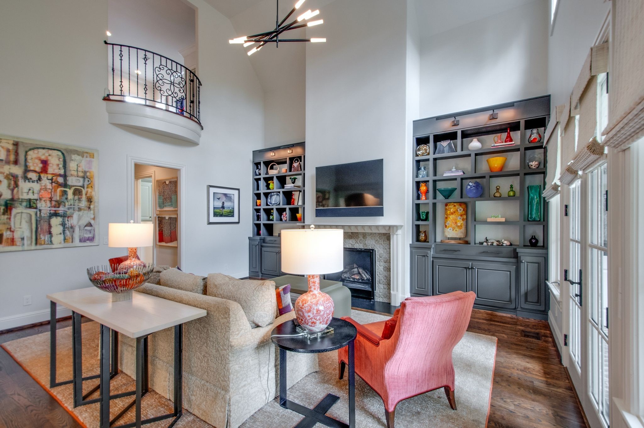 Living room with a fireplace, built-in display shelves, and a curved upstairs balcony.