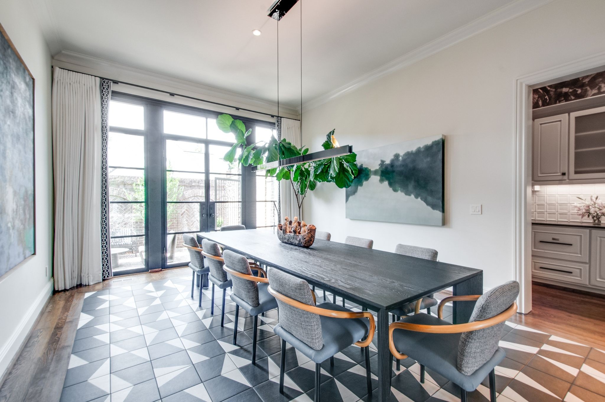 Dining room with a long dark table, geometric tile floor, and tall glass doors to a patio.