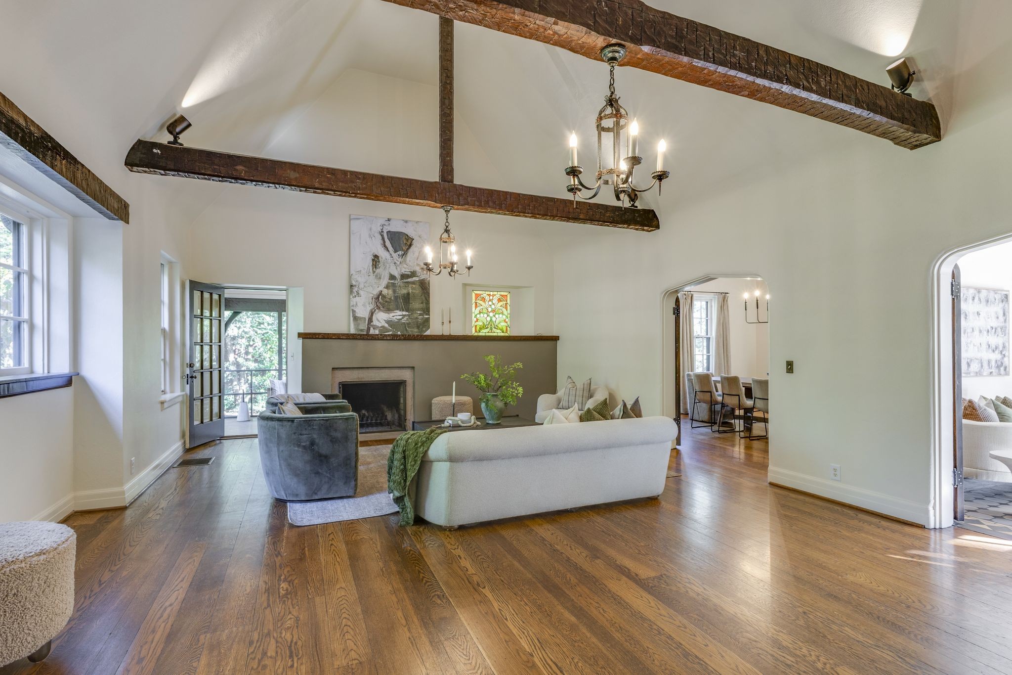 Living room with vaulted ceiling, exposed beams, fireplace, and hardwood floors.
