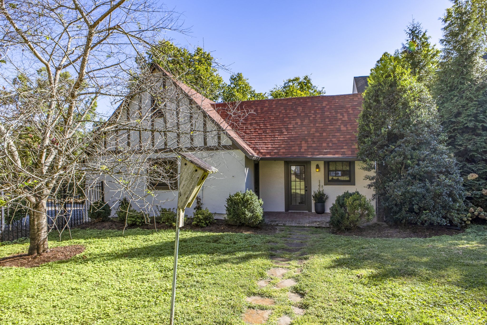 Home with a half-timbered gable, reddish-brown roof, and stone path to the entrance.